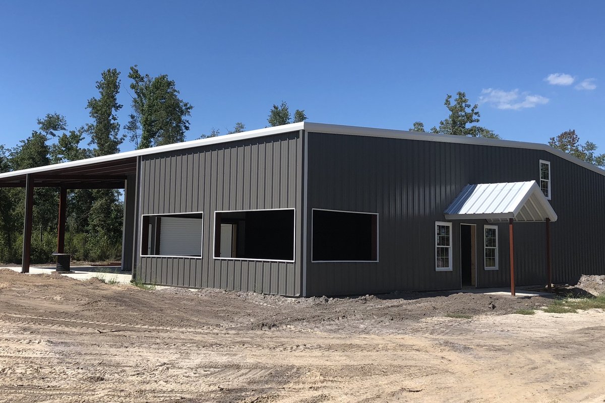 Charcoal metal building with attached open lean-to