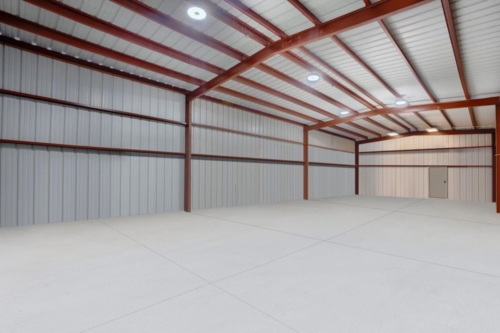Finished metal building interior with red iron framing and concrete slab